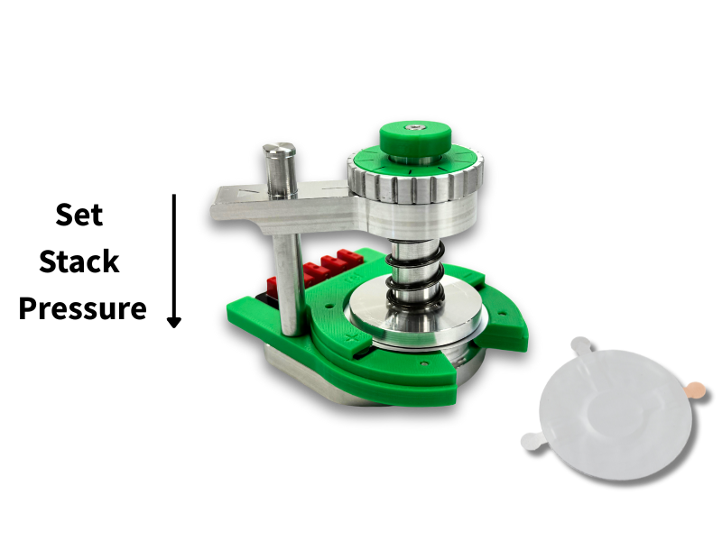 A green and silver Protocell test jig with an adjustable screw mechanism used to set and apply stack pressure to a Protocell during testing. A Protocell pouch cell is shown to the right for reference.